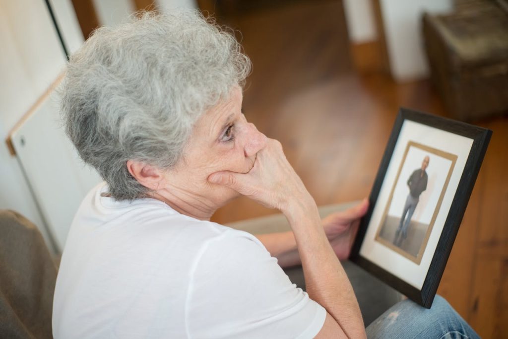 Elderly woman looking sad as she gazes at a picture of missing husband.